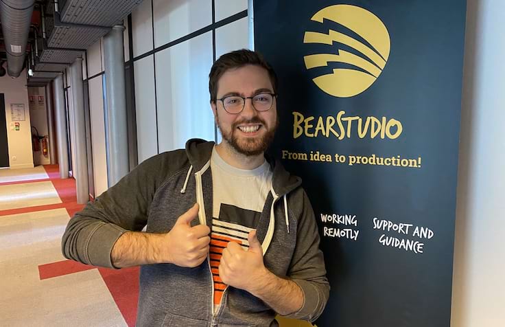 Ivan Dalmet avec sa mimick double pouce haut devant le kakémono Bear Studio